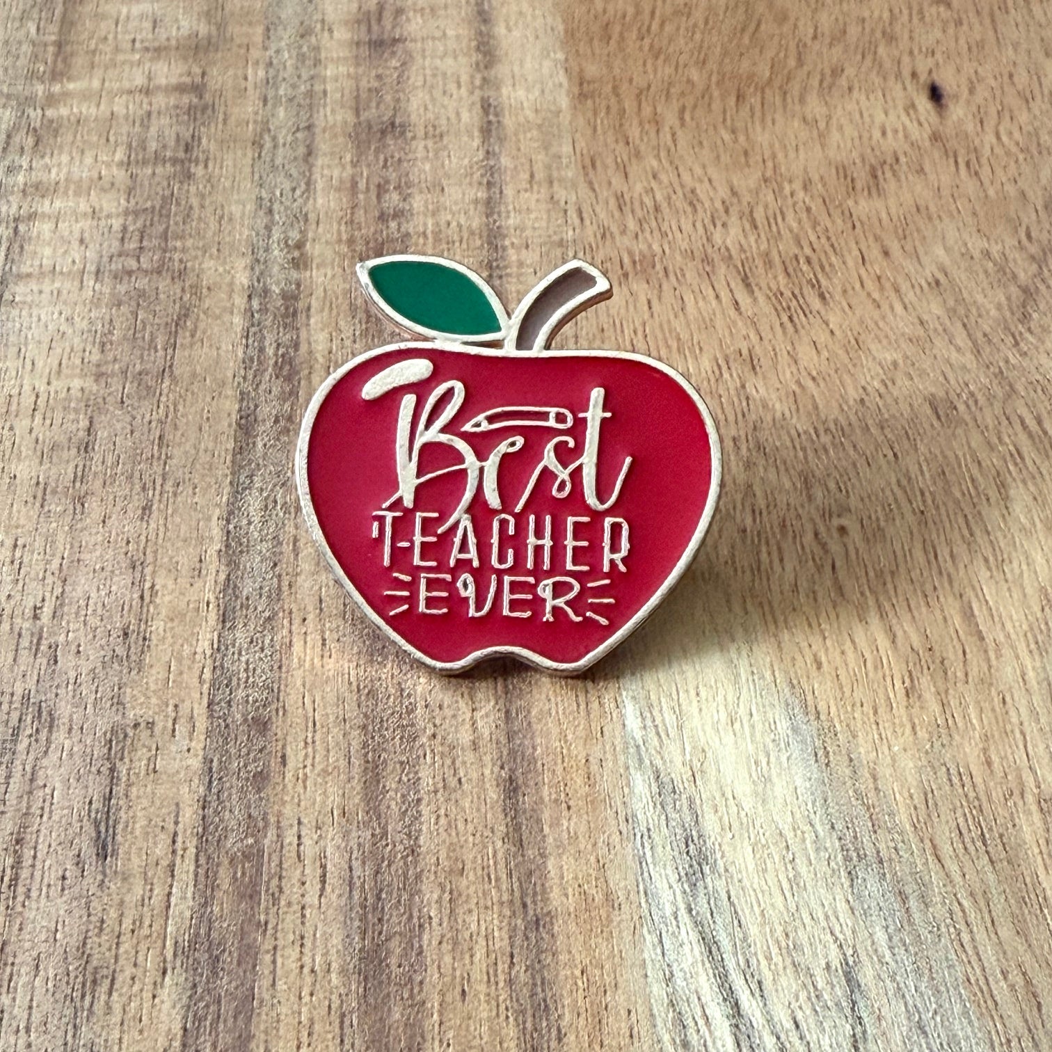 Nyssa Best Teacher pin featuring a colorful design, perfect for honoring educators on a lapel or bag accessory.