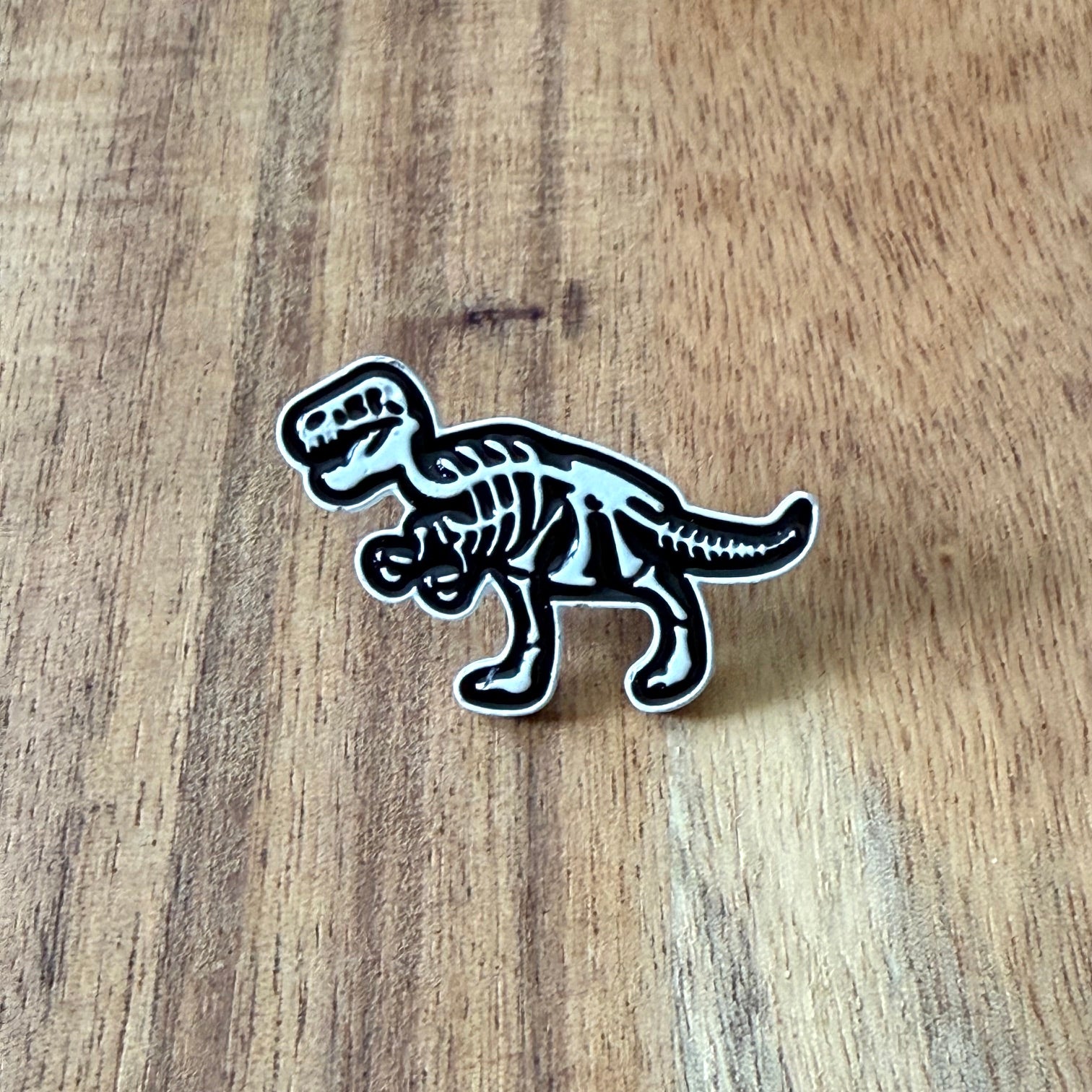 Nyssa Dino pin featuring a colorful dinosaur design, perfect for adding fun to backpacks or clothing accessories.