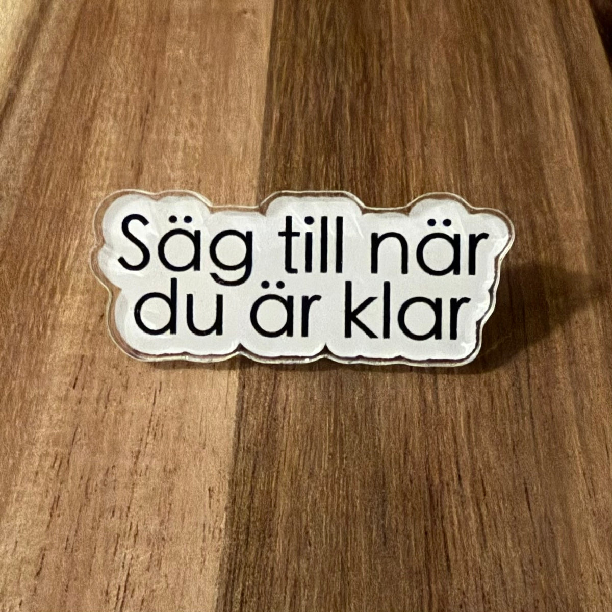Nyssa "Säg till när du är klar" pin featuring a metal safety pin with engraved text, ideal for notifying when finished.