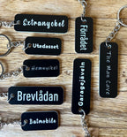 Black acrylic keychain with custom engraved text from Nyssa, featuring a sleek and modern design.