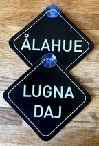Nyssa Säg det på Skånska bilskylt with Lugna Daj design, featuring bold black text on a white background, mounted on a vehicle.
