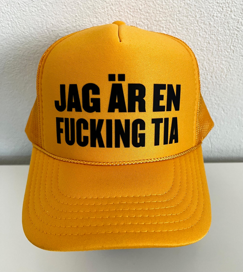 Nyssa trucker cap with bold "JAG ÄR EN FUCKING TIA" slogan, featuring classic mesh back and adjustable snap closure.