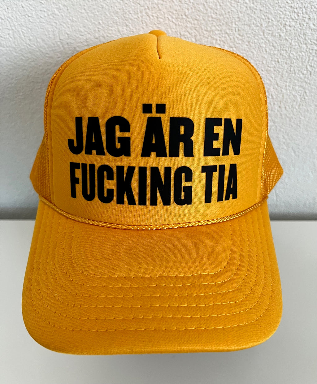 Nyssa trucker keps with bold printed slogan "JAG ÄR EN F**KING TIA" on the front, adjustable mesh back and structured design.