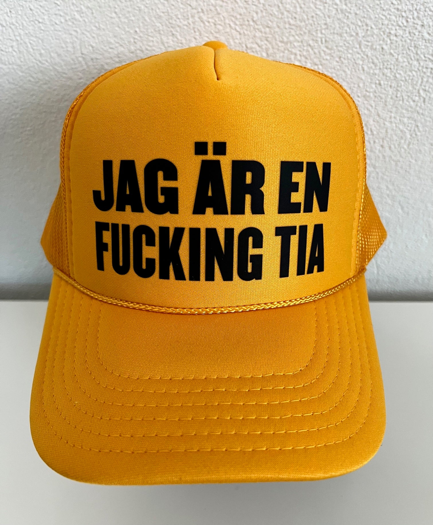 Nyssa trucker keps with bold printed slogan "JAG ÄR EN F**KING TIA" on the front, adjustable mesh back and structured design.