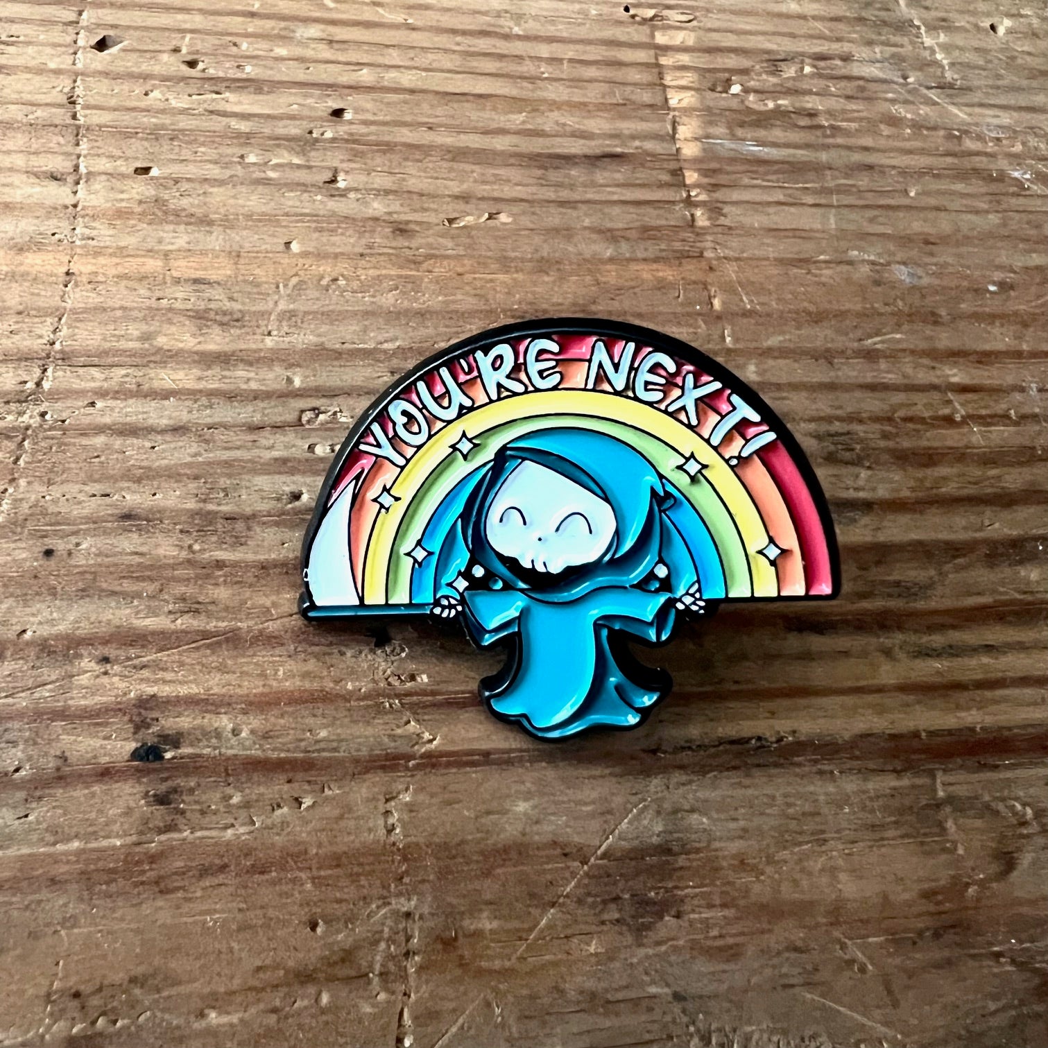 Nyssa "You’re Next!" enamel pin featuring bold black lettering on a circular design, perfect for jackets or backpacks.