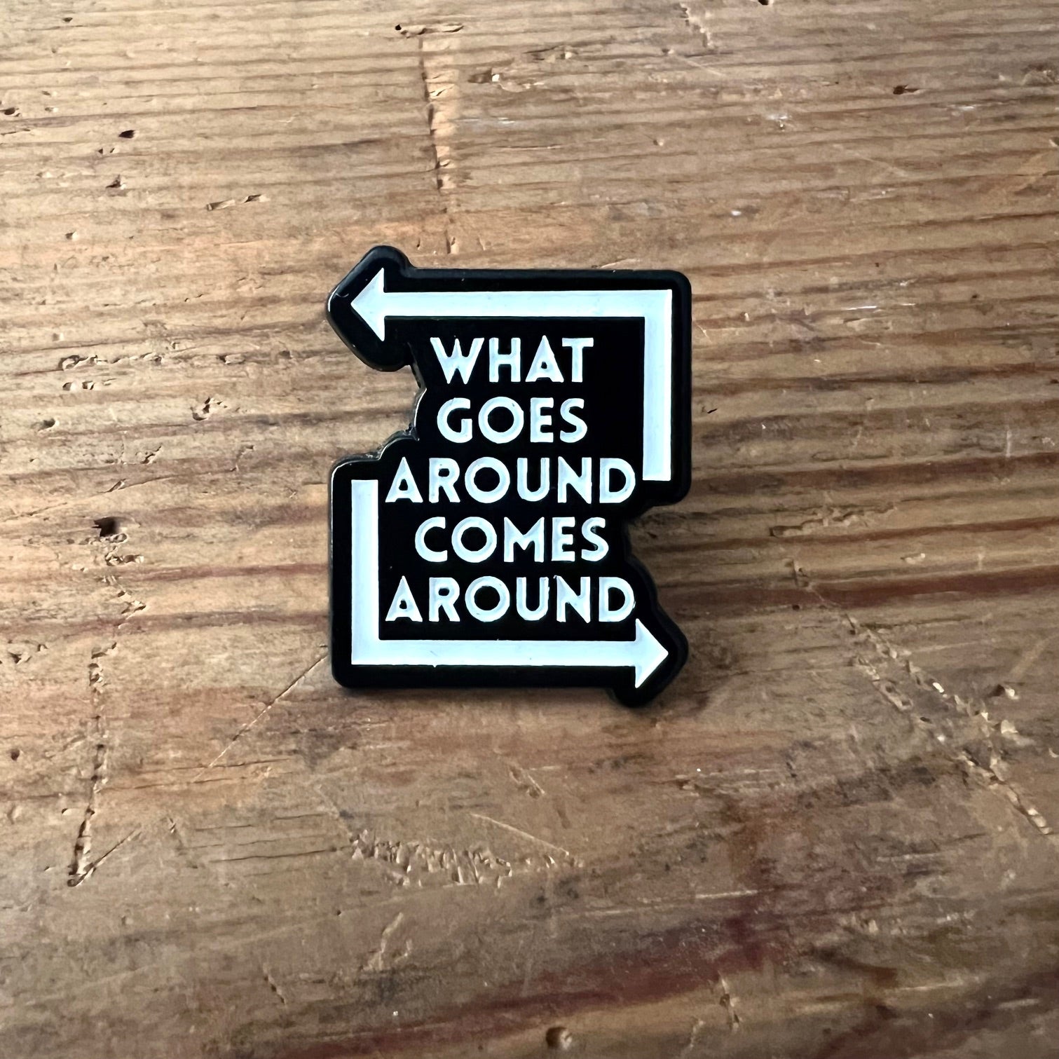 Nyssa "What Goes Around Comes Around" pin featuring a circular design, perfect for accessorizing or collecting.