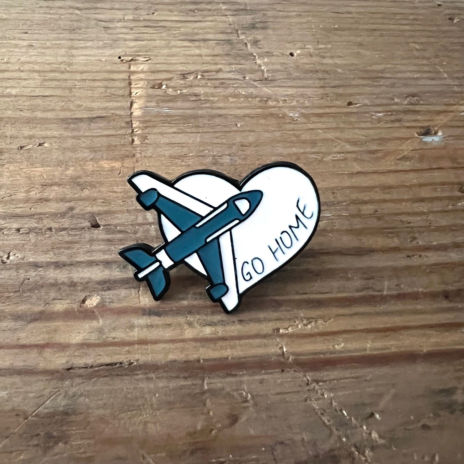 Nyssa "Go Home" enamel pin featuring a colorful design, perfect for backpacks or jackets, showcasing vibrant details.