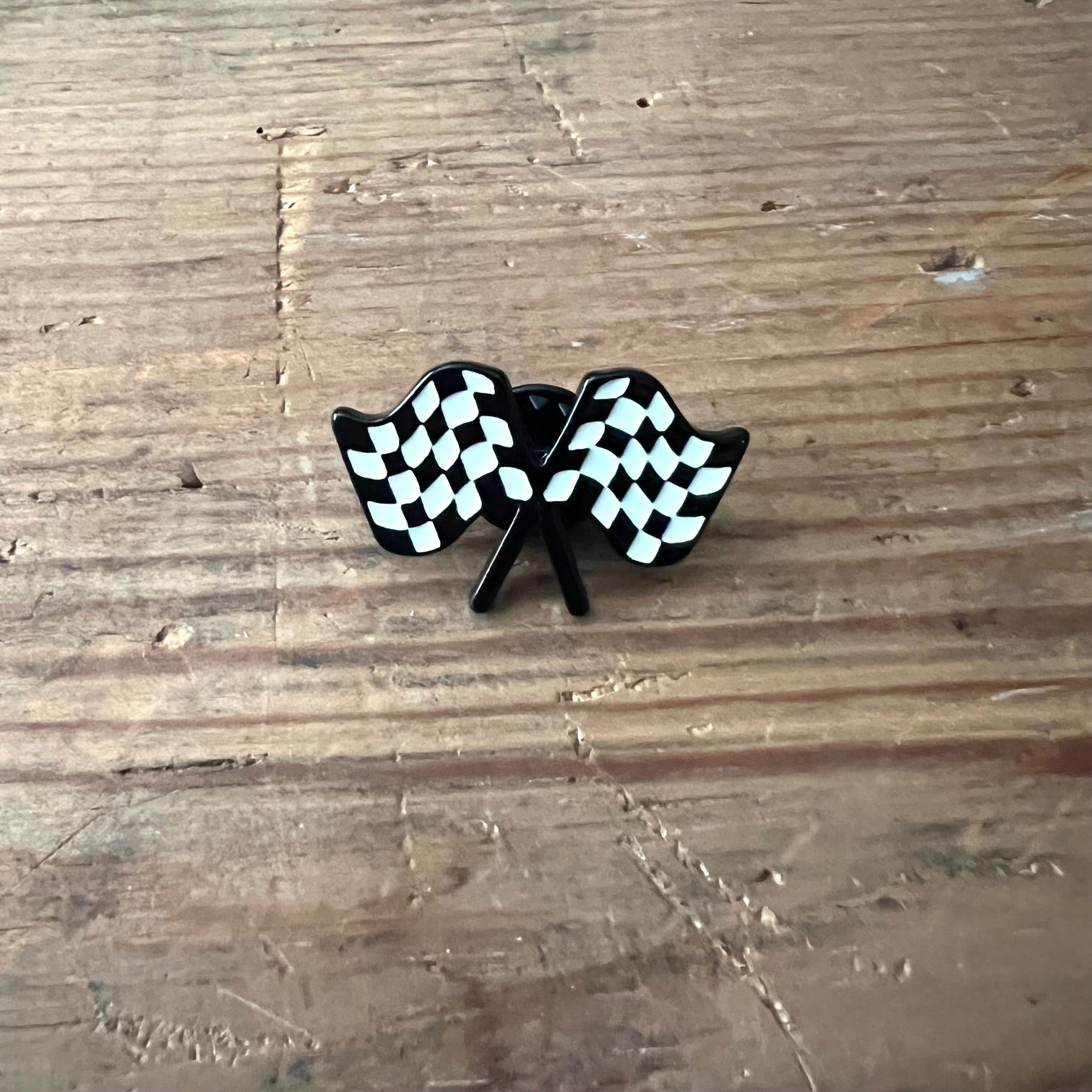 Nyssa checkered flag pin, small metal lapel accessory with black and white checkered pattern for racing fans.