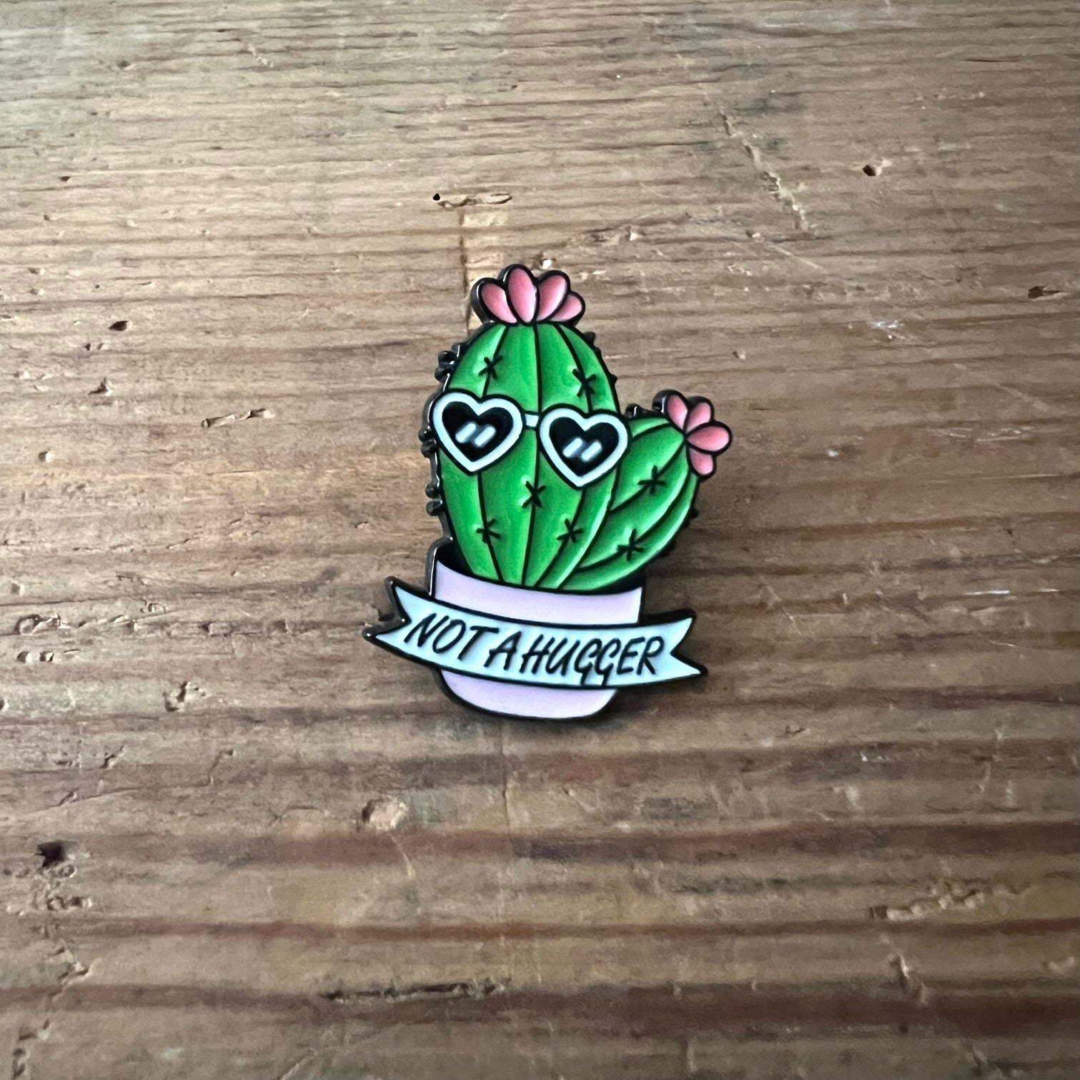 Nyssa "Not a Hugger" pin showing a small metal pin with humorous text, perfect for accessorizing clothing or bags.