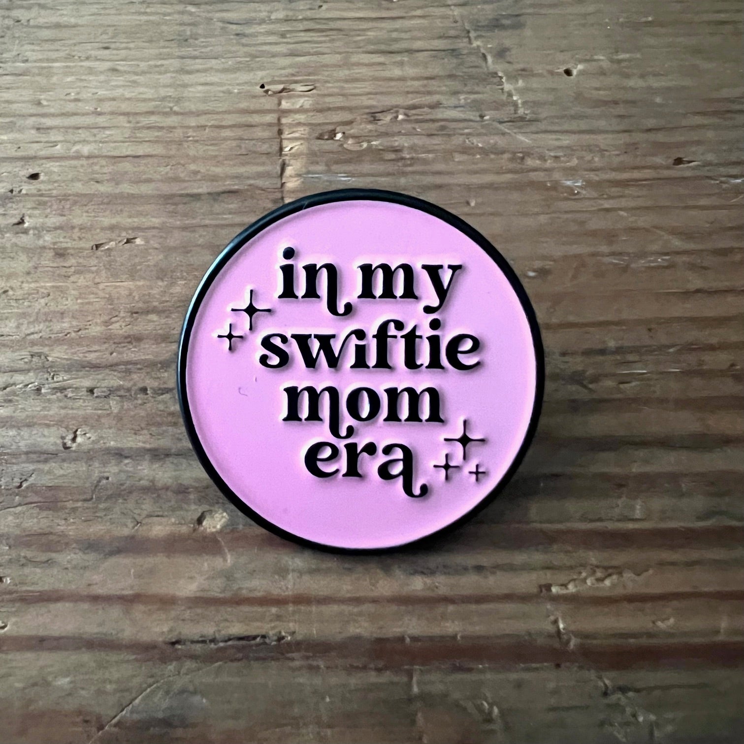 Nyssa "In my Swiftie mom era" pin featuring a colorful design, perfect for fans of Taylor Swift and mom-themed accessories.