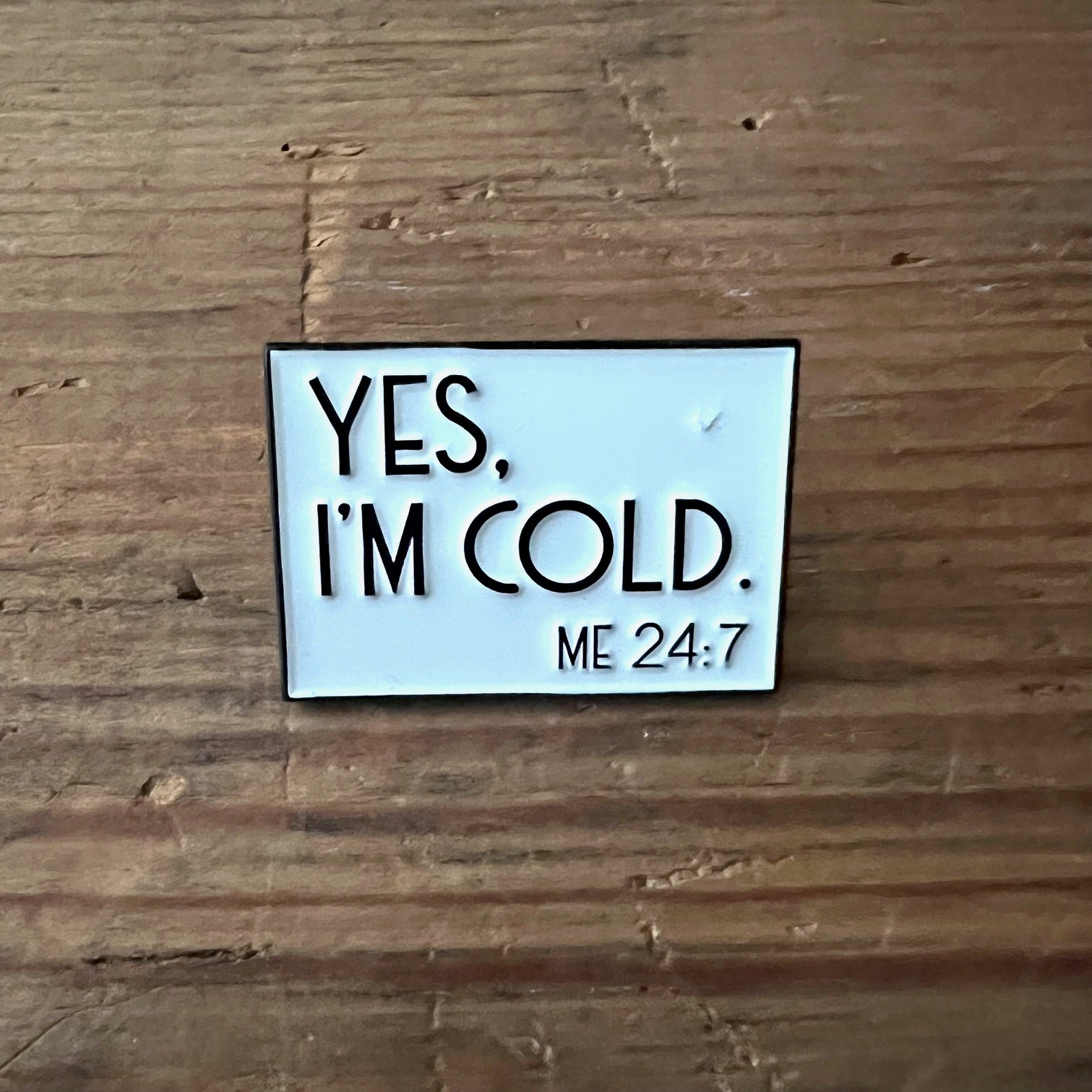 Nyssa "Yes, I’m Cold" pin featuring bold text, designed as a stylish accessory for jackets or backpacks.