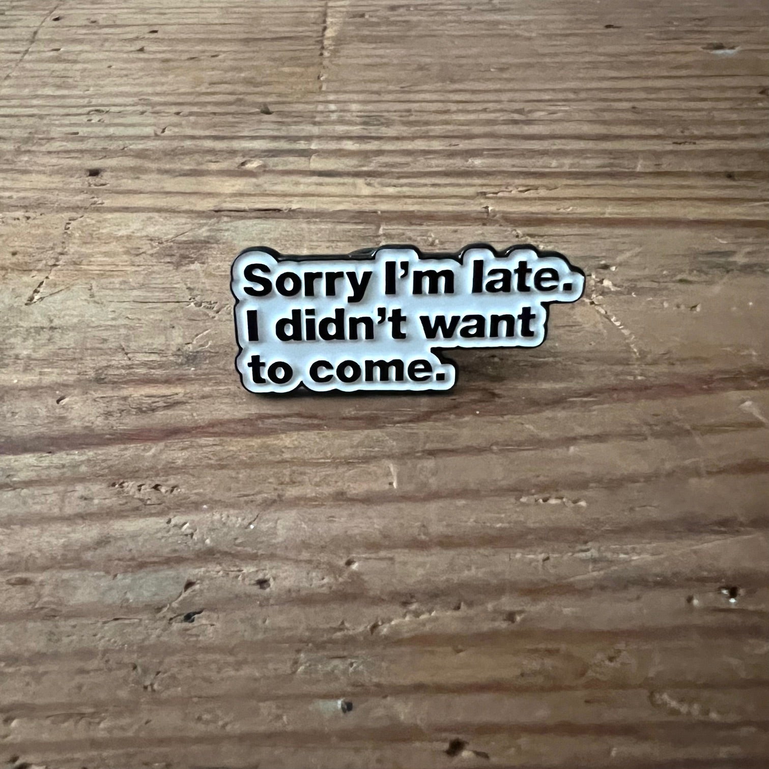 Nyssa "Sorry I’m late. I didn’t want to come" pin, metal badge with humorous message, featuring a safety pin backing.