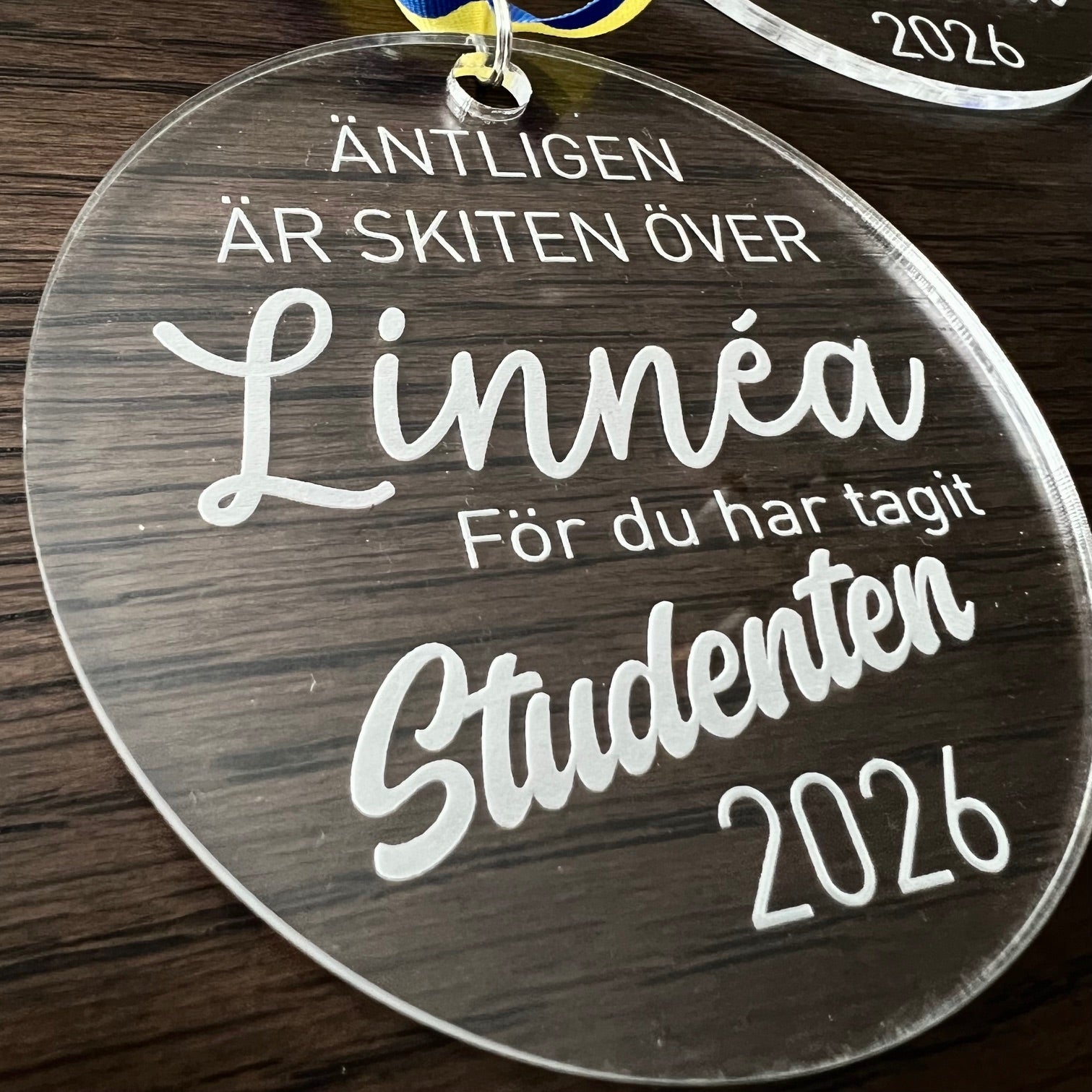 Nyssa studenthänge with "Skiten är över" design, featuring a colorful cartoon illustration on a circular pendant.