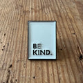Nyssa Be Kind pin showing a colorful enamel design with the phrase "Be Kind" on a metal pin backing.