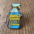 Yellow "Positive Vibes" pin by Nyssa featuring a cheerful design, perfect for accessorizing bags or clothing.
