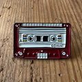 Nyssa pin with tape design, small metal lapel pin featuring a tape motif, perfect for accessories and collectibles.