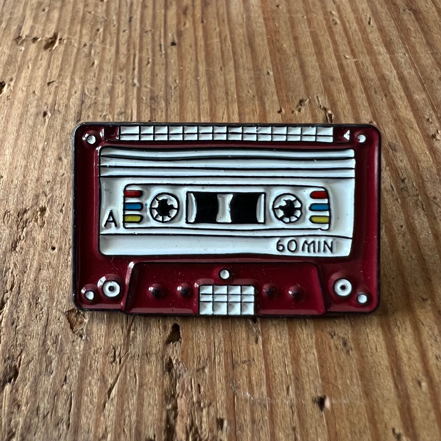 Nyssa pin with tape design, small metal lapel pin featuring a tape motif, perfect for accessories and collectibles.