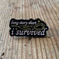 Nyssa "I Survived" pin featuring a small, round metal pin with bold text, perfect for clothing or accessories.