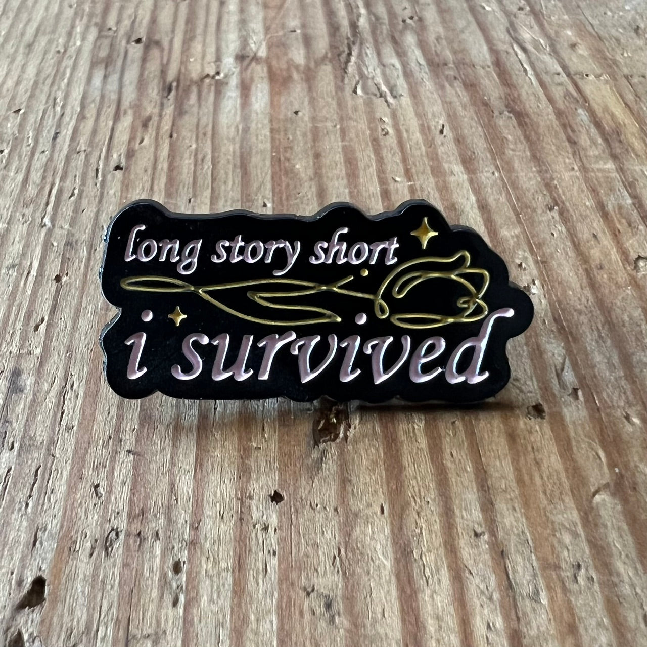 Nyssa "I Survived" pin featuring a small, round metal pin with bold text, perfect for clothing or accessories.