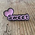 Nyssa Sweet pin featuring a colorful, decorative design on a metal pin for accessorizing or collection.