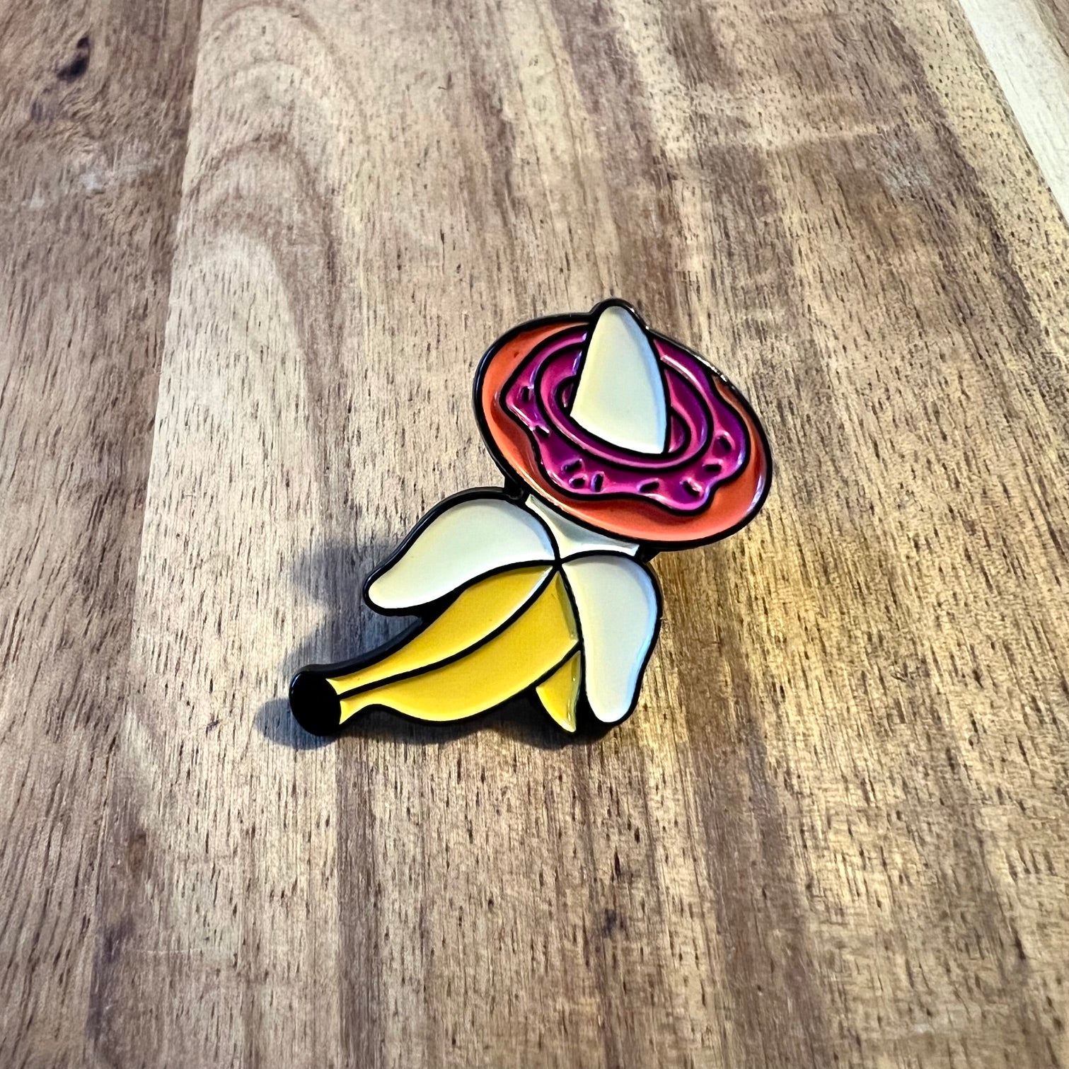 Nyssa BananaDonut pin featuring a colorful banana and donut design on a metal pin backing.