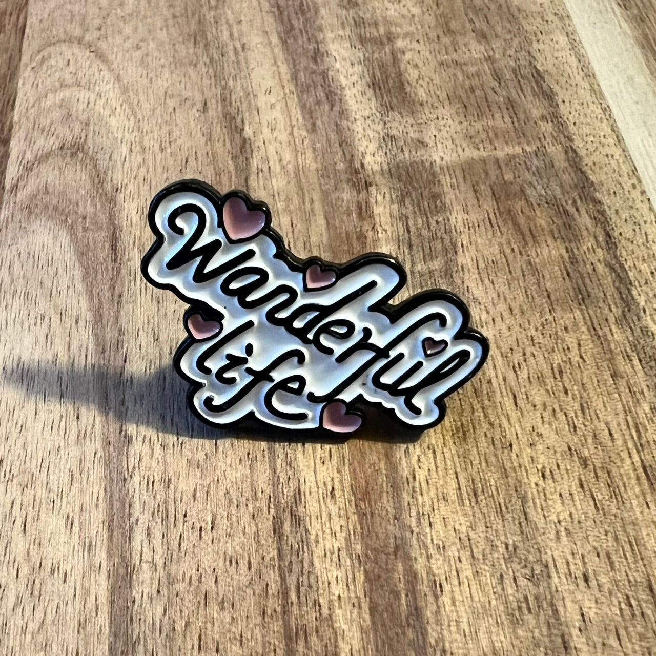 Nyssa Wanderful Life pin showing a colorful, stylish enamel pin with the phrase "Wanderful Life" on a white background.