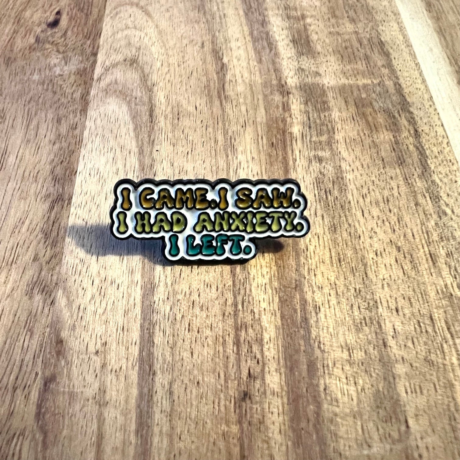 Nyssa "I Came, I Saw..." pin featuring a colorful design, showcasing a metal pin with engraved text on a plain background.