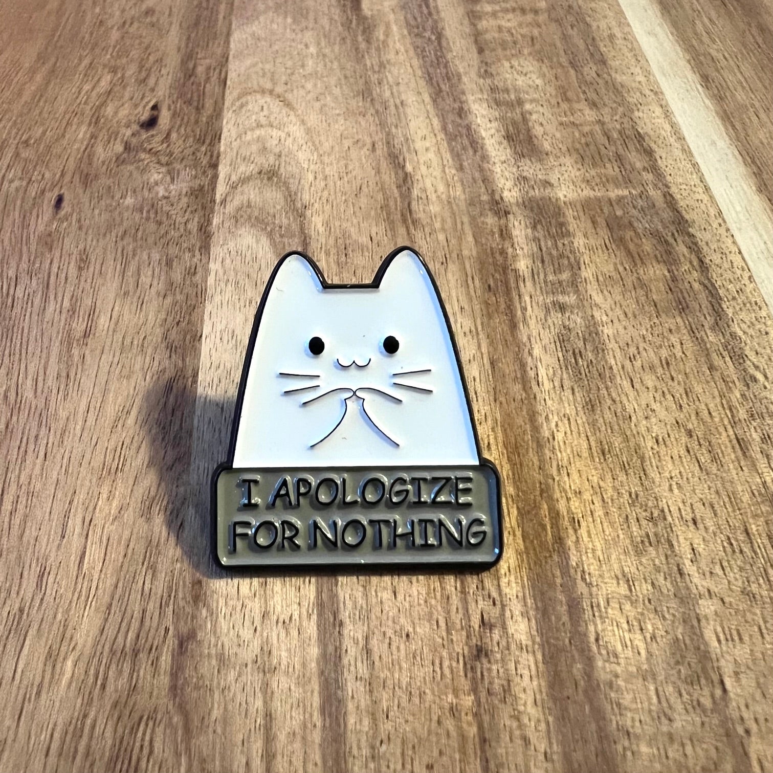 Nyssa "I Apologize..." pin featuring a small, stylish metal lapel pin with engraved text, designed for clothing or accessories.