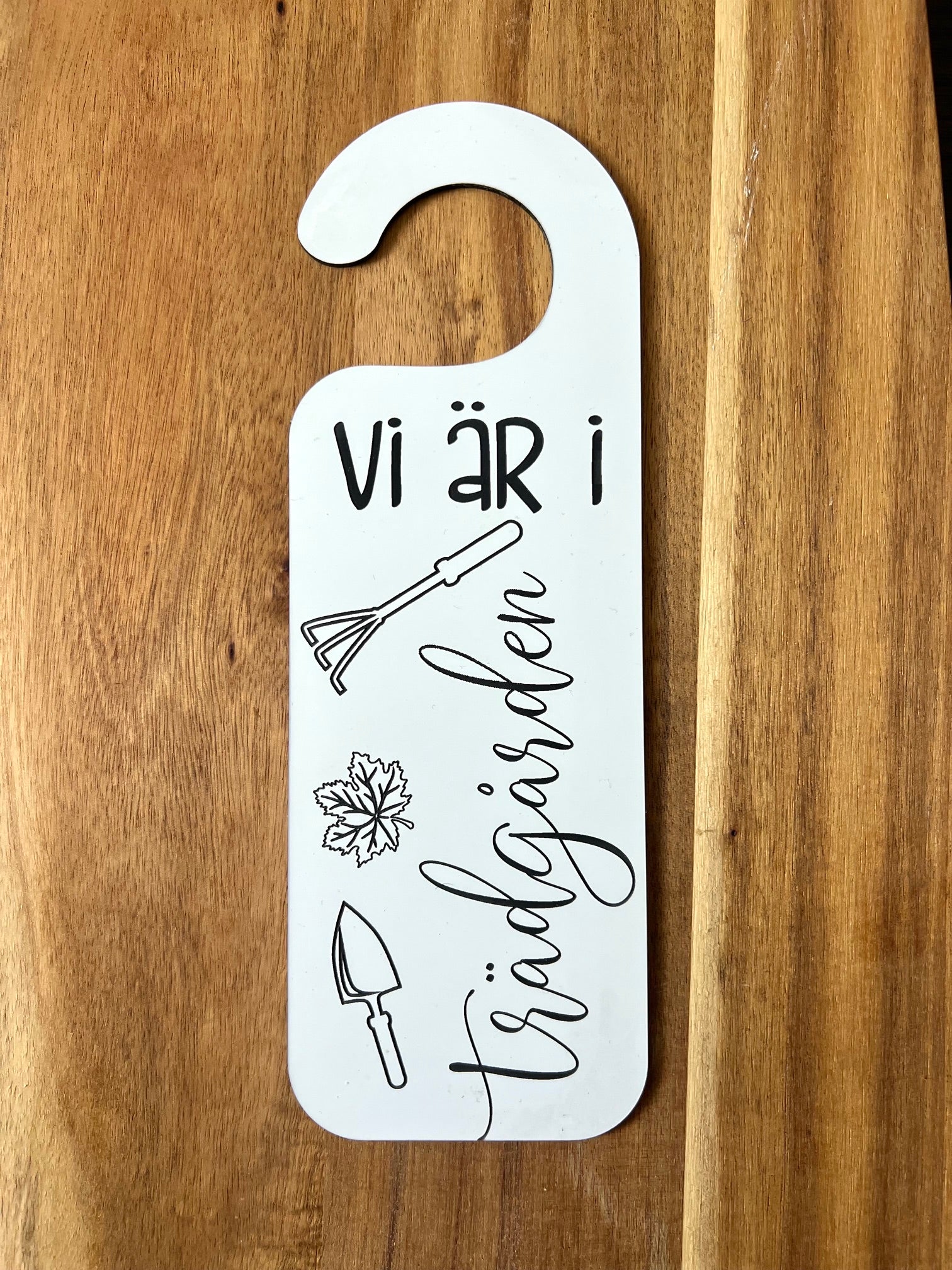 Nyssa Dörrhänge skylt with "Vi är i trädgården" text, featuring garden-themed design, hanging indoors or outside.
