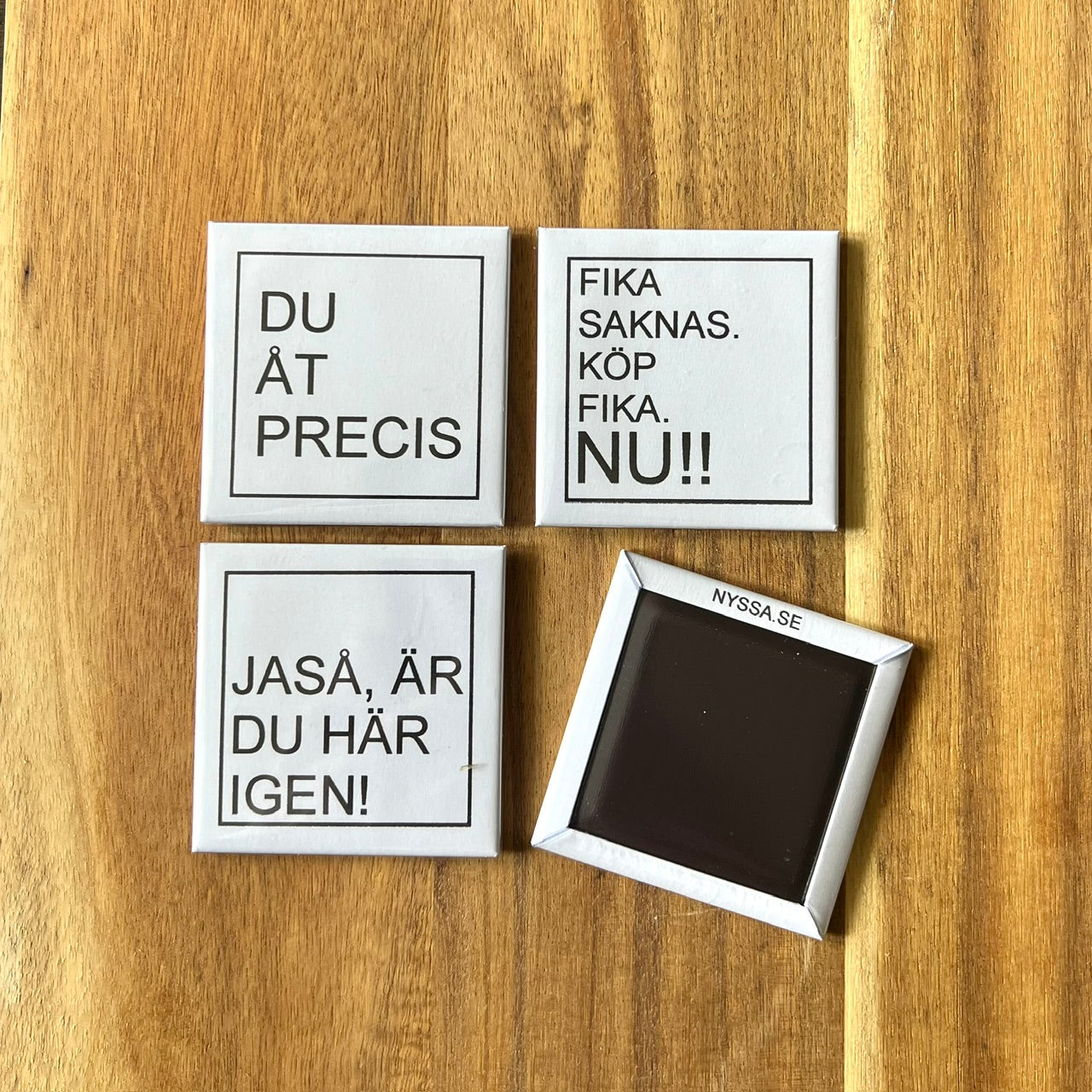 Set of four Nyssa LET'S FIKA refrigerator magnets with colorful coffee cup and pastry designs on a white background.