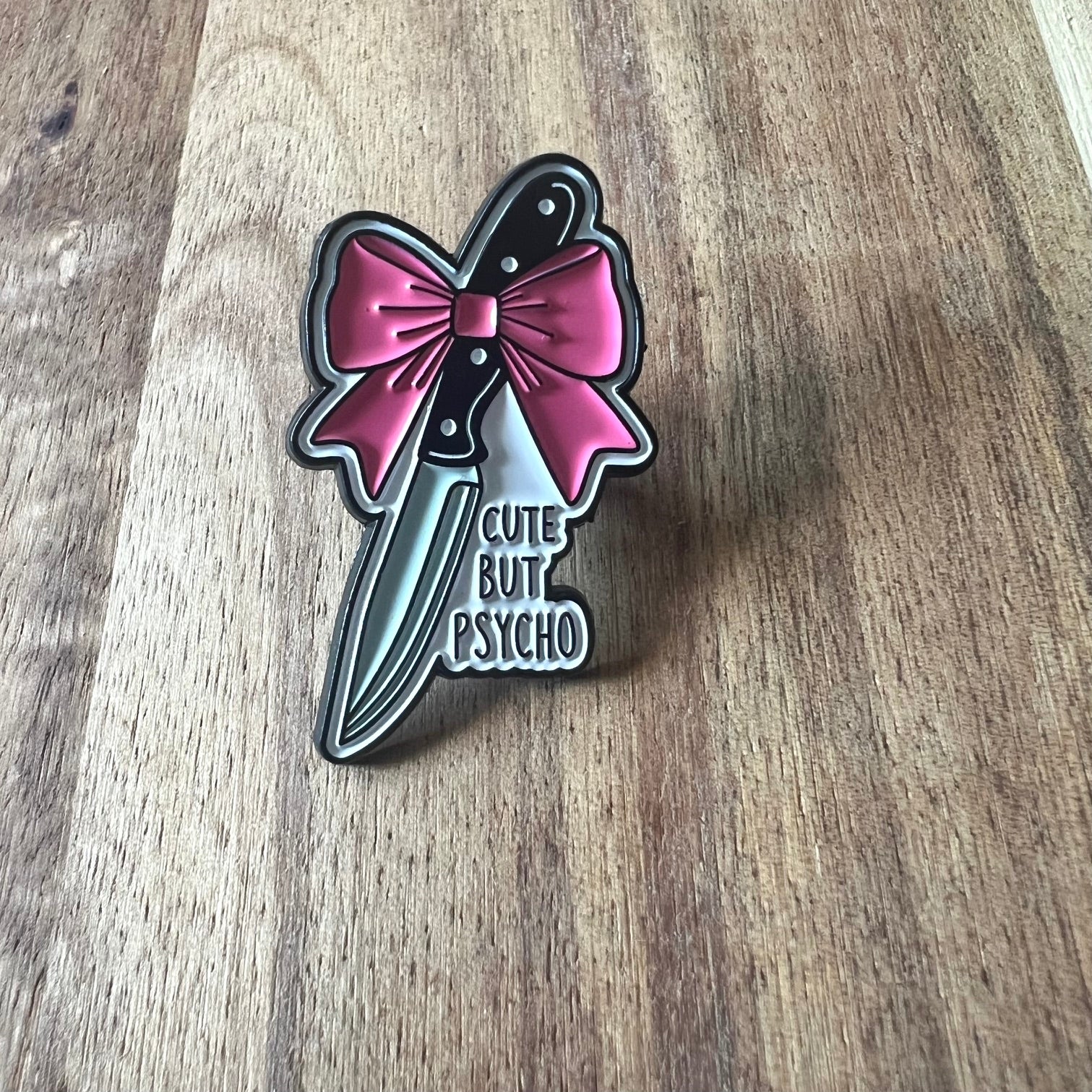 Nyssa cute but psycho pin featuring a playful, colorful design with a cartoon character on a metal pin back.