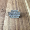Nyssa "I Survived" pin featuring a metal safety pin design with bold lettering, perfect for clothing or accessories.