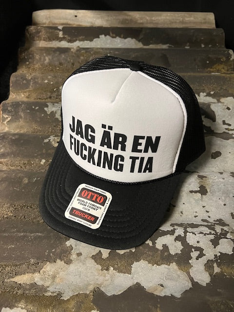 Nyssa trucker cap with bold "Jag är en fucking Tia" slogan, featuring classic mesh back and adjustable strap design.